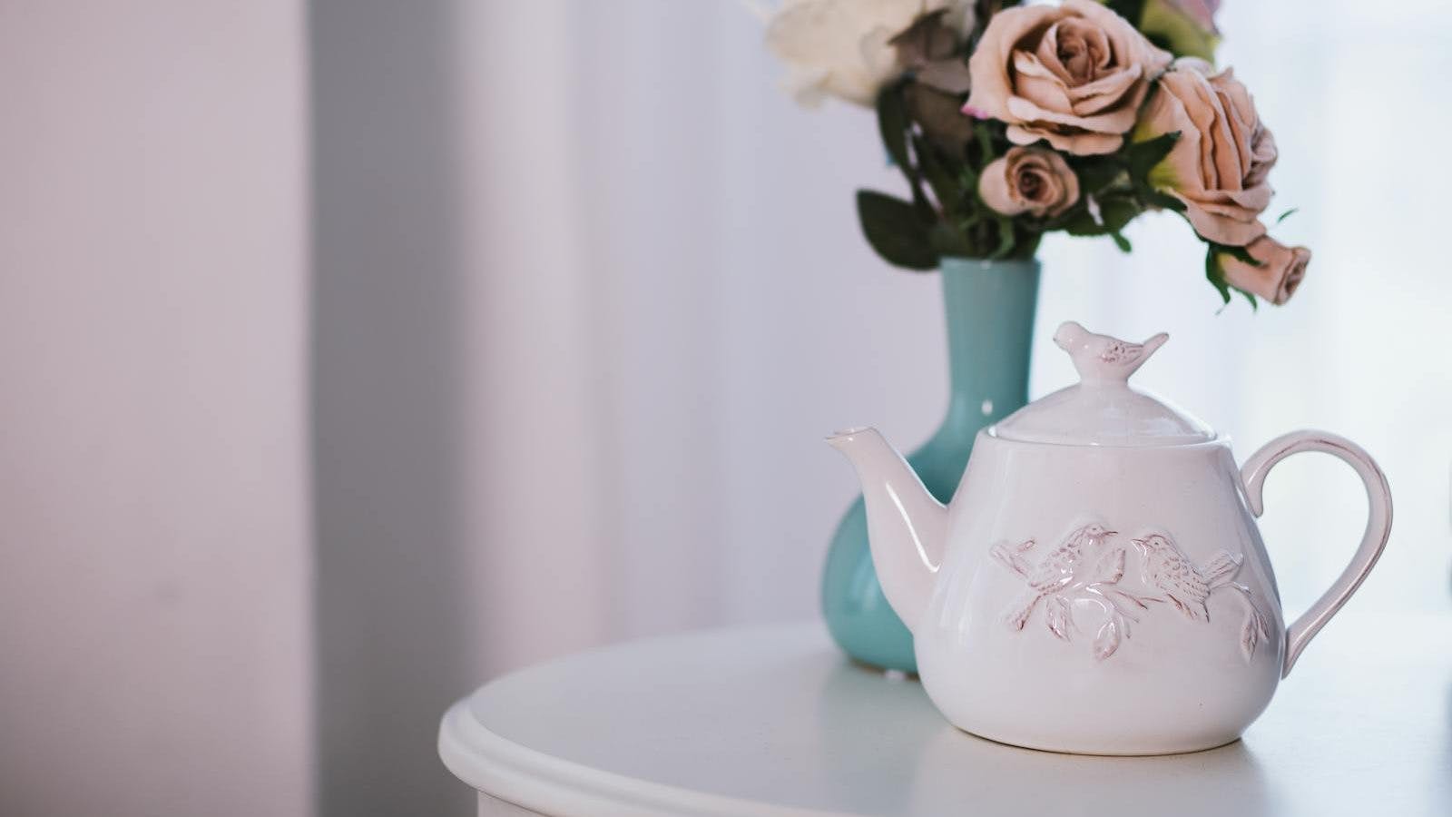 White Ceramic Teapot Near Flower Arrangement on White Surface