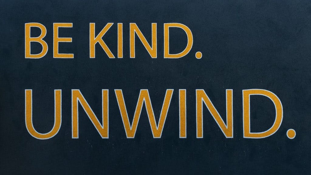 a sign that says be kind of unwind