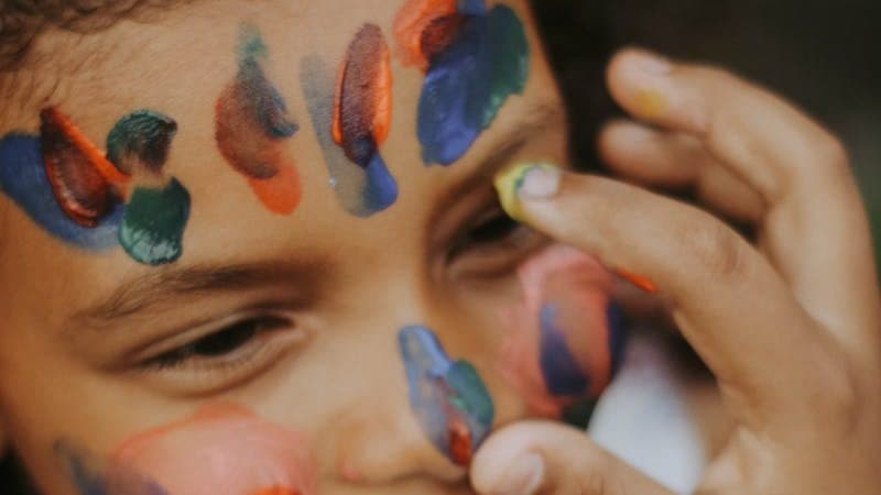 Little Girl Smiling and Person Painting on Her Face