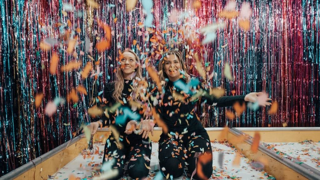 Two Women Kneeling While Throwing Confetti