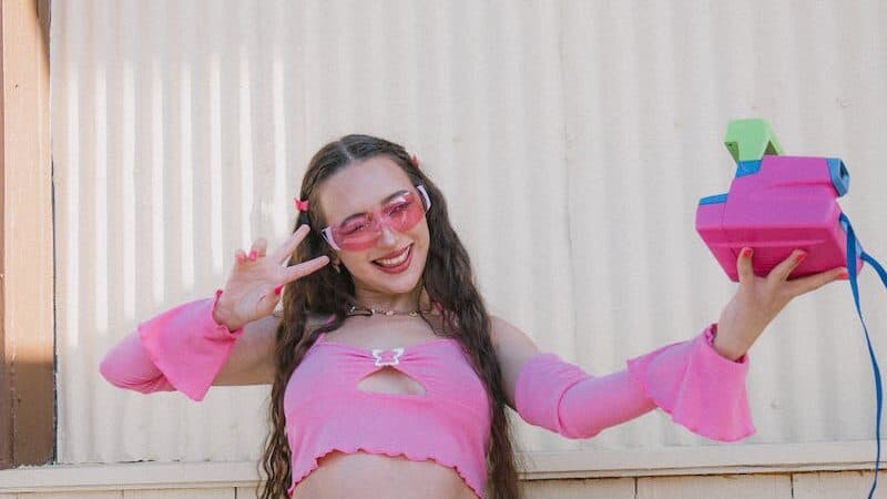 A girl in a pink top and skirt holding a pink purse
