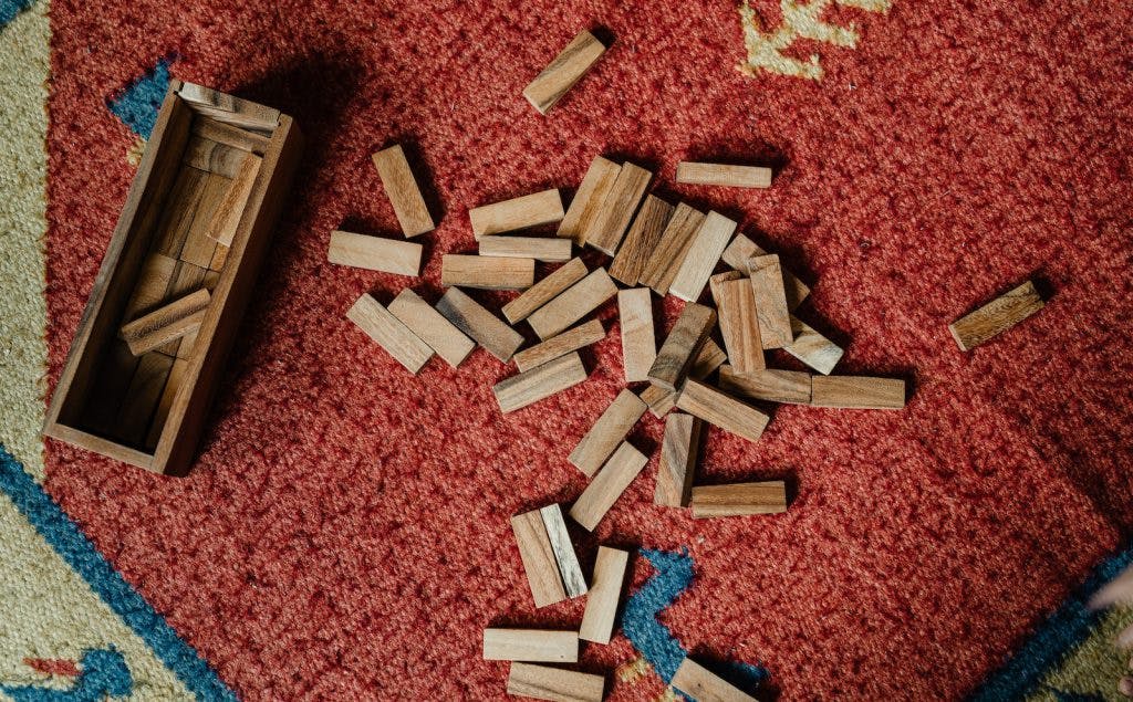 Top view of wooden box and pile of blocks for playing in jenga tower game arranged on floor carpet