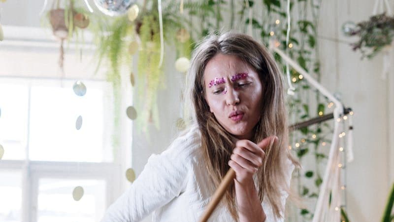 Woman in White Long Sleeve Shirt Holding Brown Wooden Stick