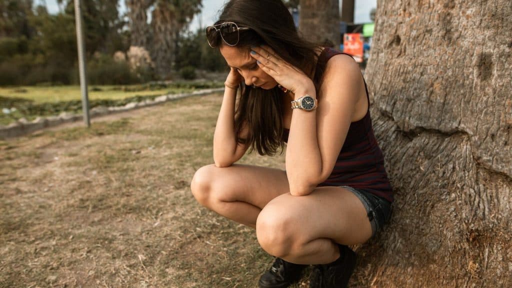 Photo of a Woman Crouching while Her Hands are on Her Head