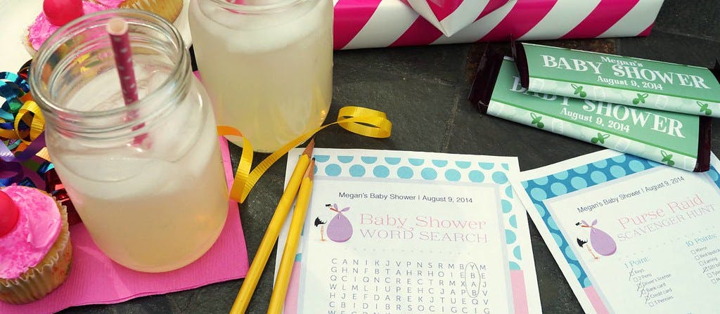 baby shower games and lemonade in a mason jar glass with personalized candy wrappers and pink frosting chocolate cupcakes