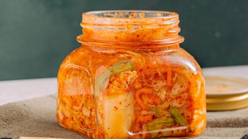 Clear Glass Jar with Kimchi beside the Wooden Chopsticks