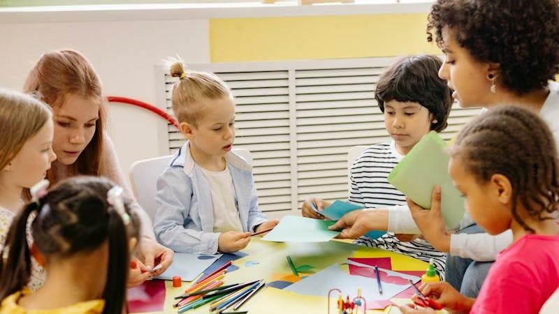 Children Sitting on Chairs in Front of Table With Art Materials