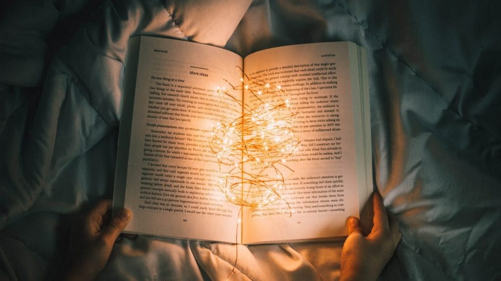 person holding string lights on opened book