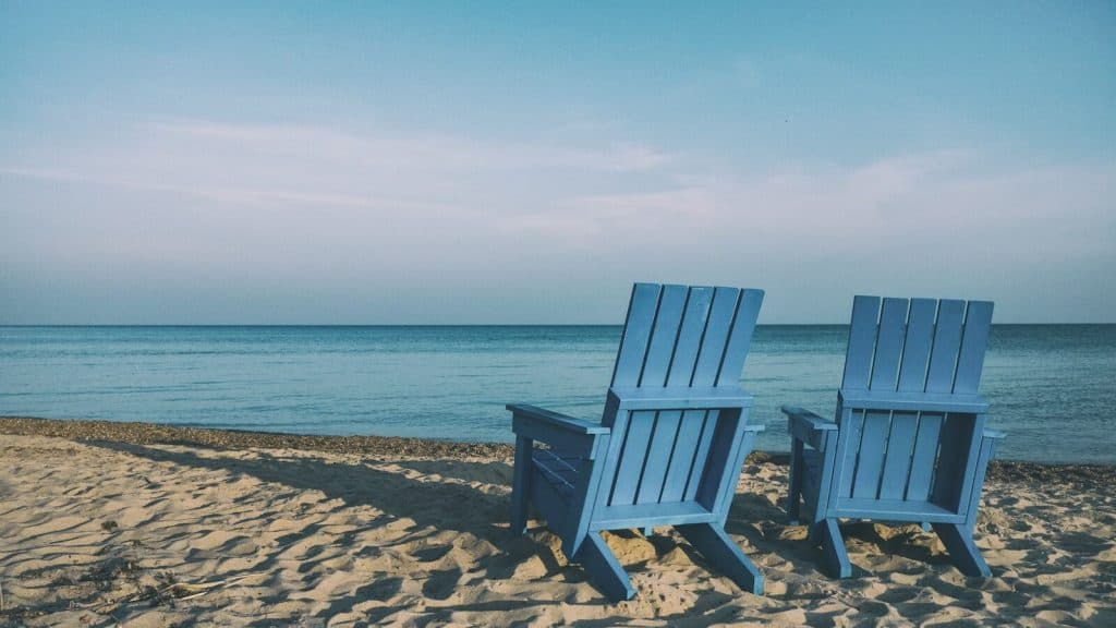 two blue beach chairs near body of water