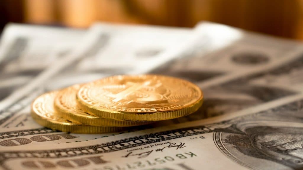 three round gold-colored coins on 100 US dollar banknotes