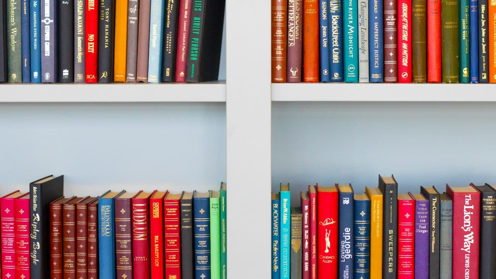 assorted-title book lot placed on white wooden shelf