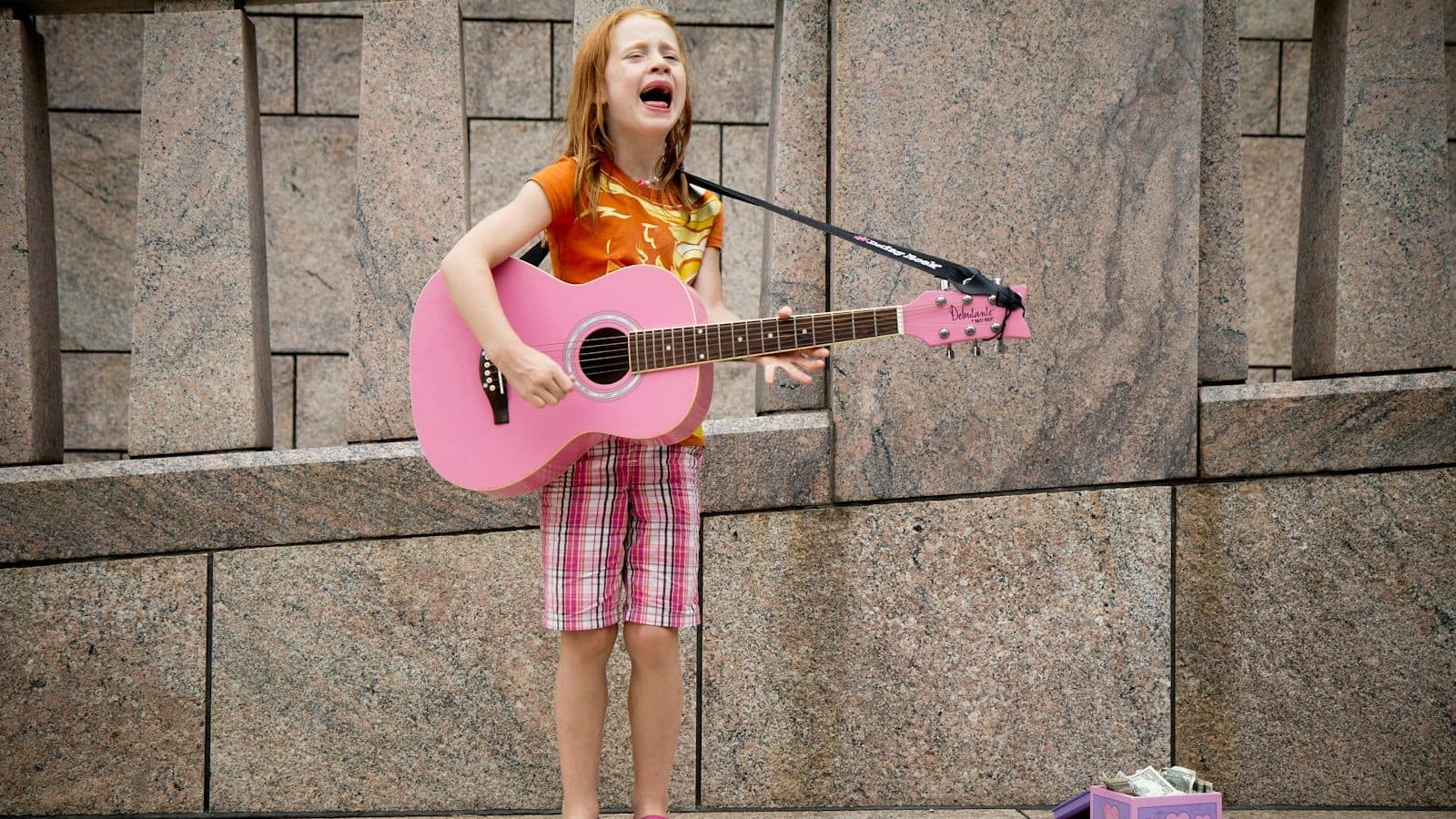 girl playing guitar near wall