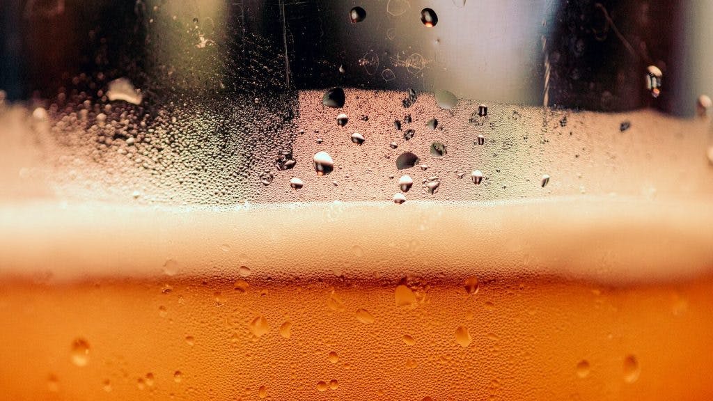 a close up of a glass of beer with drops of water