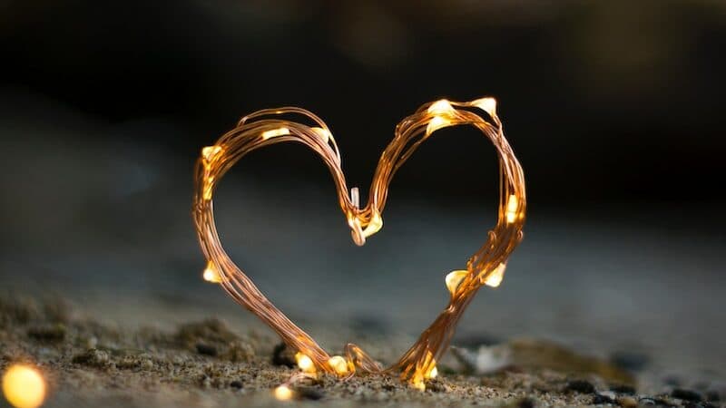 close-up photography of heart shaped fairy lite on brown sand