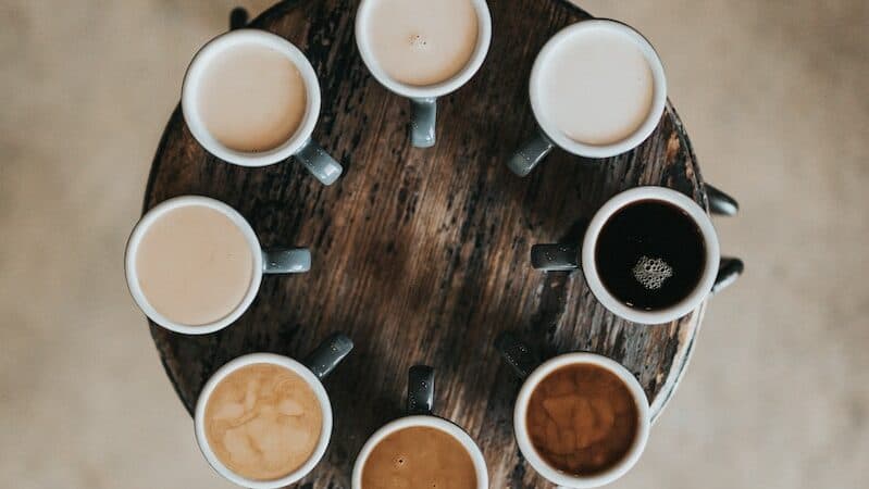 flat lay photography of eight coffee latte in mugs on round table