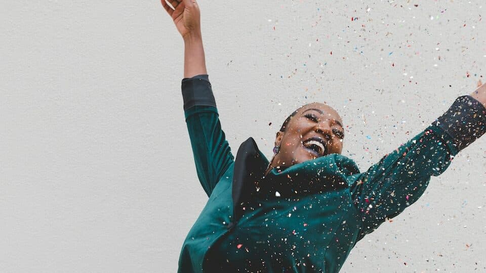 woman in green jacket raising her hands