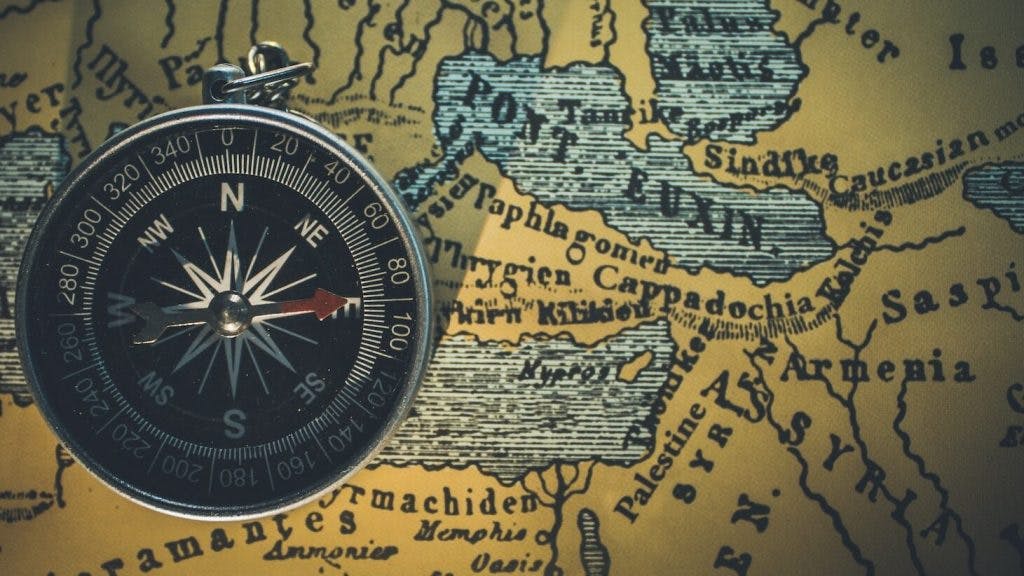 round gray framed compass on brown map