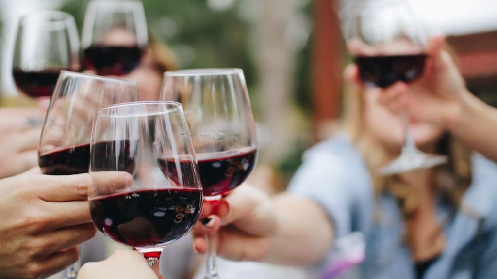 people tossing their red wine glasses