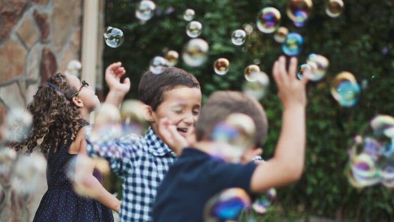 boy in blue and white polka dot shirt playing bubbles