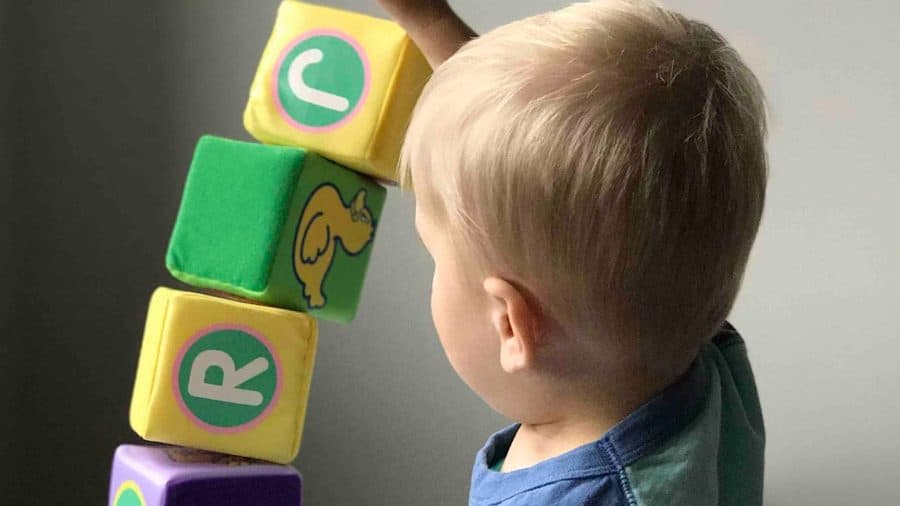 boy playing cube on white wooden table